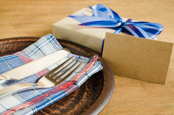 Prato rústico com garfo, faca e um guardanapo xadrez ao lado de um presente do dia dos pais
