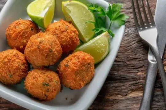 Bolinhos de bacalhau empilhados com limões do lado